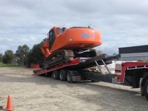 Our fleet's prized possession, the advanced Mac Excavator, towing an industrial machine for delivery on-site