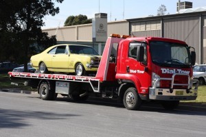A yellow Holden Monaro being towed from the service centre to it's owner's hoem