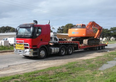 Our fleet's prized possession, the advanced Mac Excavator, towing an industrial machine for delivery on-site