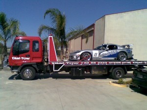 Clipper sponsored race car being towed with Dial-a-Tow's prestige car towing tilt truck