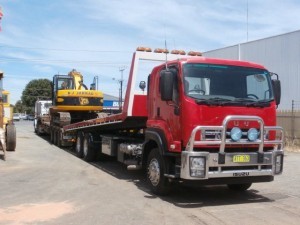 Our road digger transporting heavy machinery using tilt truck